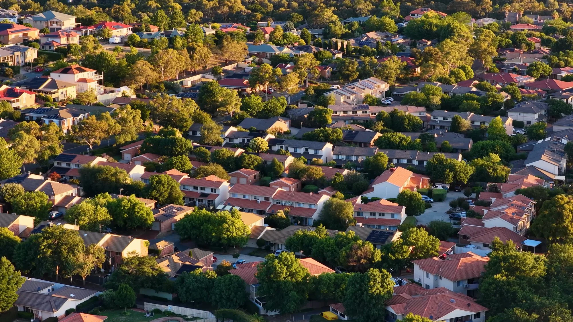 Aerial view of a dense residential neighborhood of tile-roofed houses among green trees