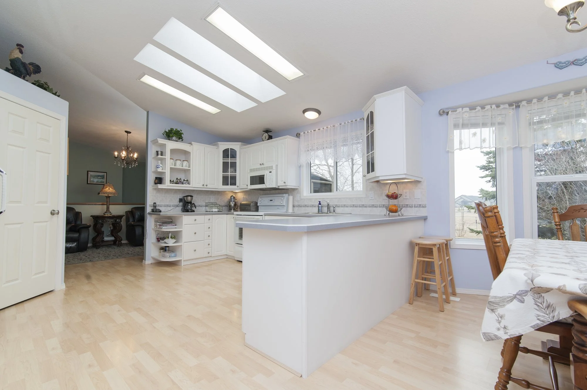 Bright kitchen with white cabinets, a breakfast bar, skylights and a wood floor