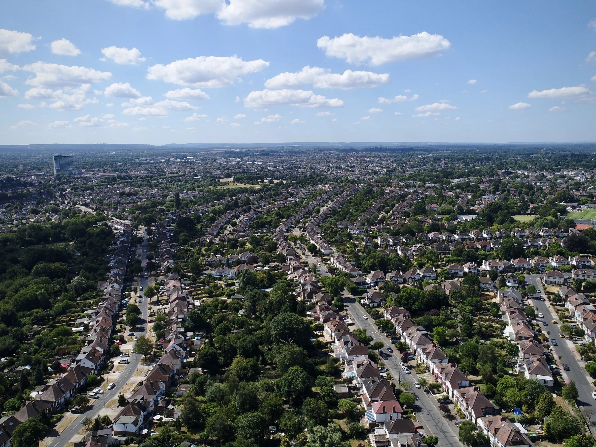Aerial view of tree-lined residential streets and rows of houses under a blue sky