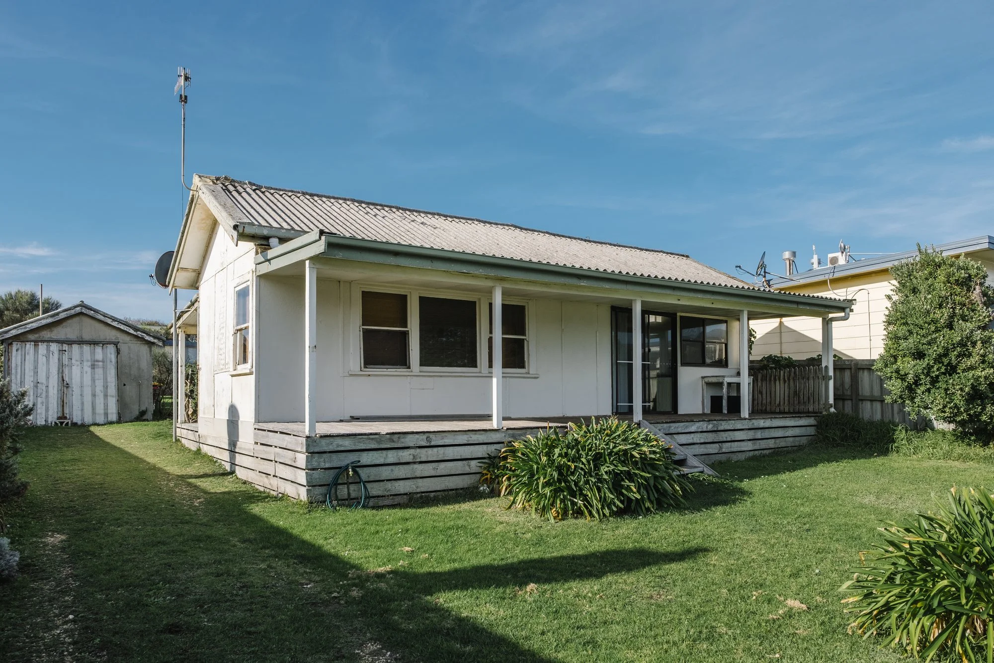 Single-story white house with a covered porch and a lawn under a blue sky